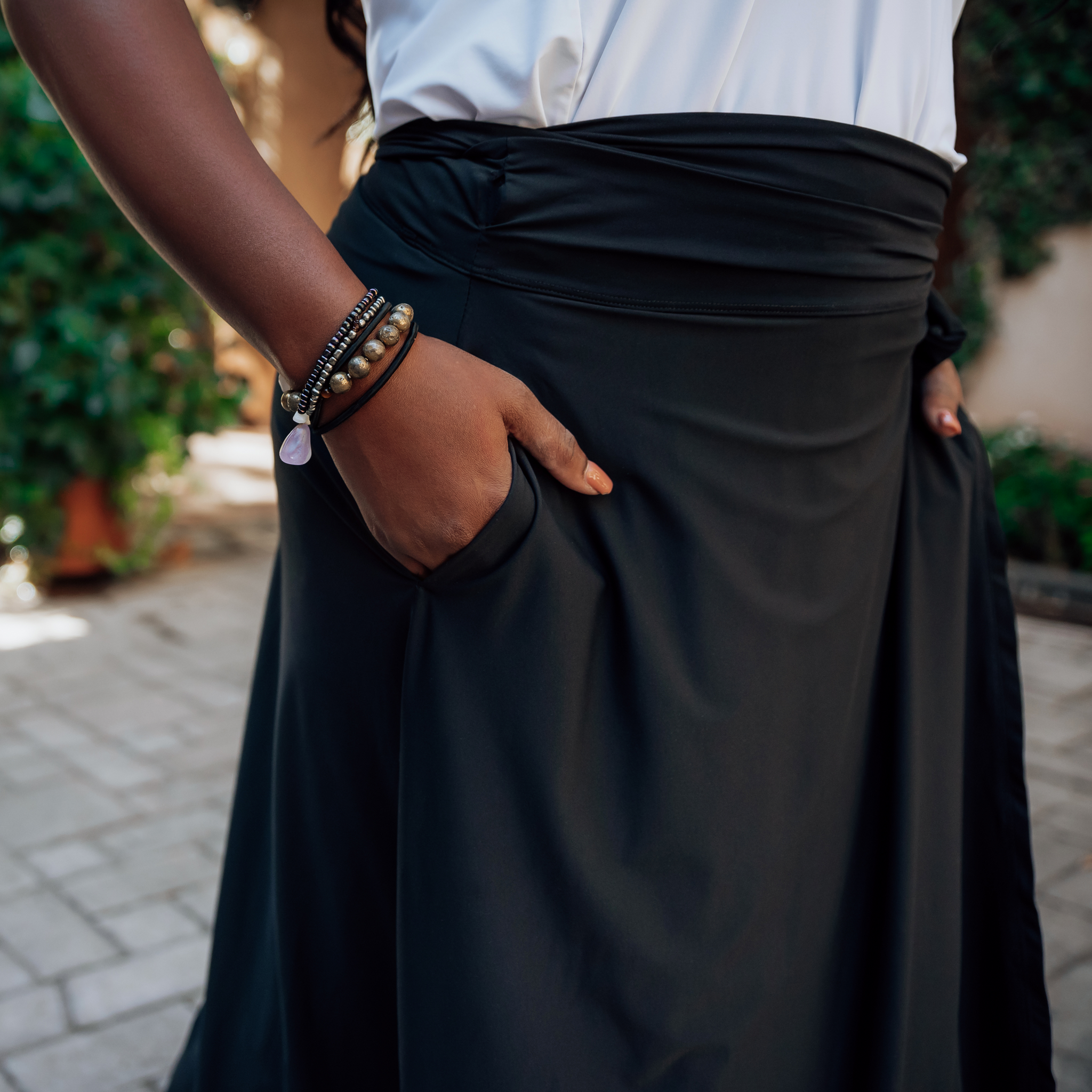 close up of someone wearing a black wrap skirt with their hands in the skirt pockets